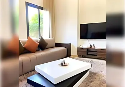 a living room with a couch and a table at Ehden Properties - Appt spacieux dans la prestigieuse River Palm Marrakech in Marrakech
