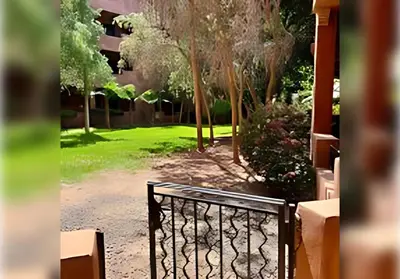 a gate in front of a yard with trees at Ehden Properties - Appt spacieux dans la prestigieuse River Palm Marrakech in Marrakech
