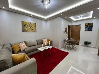 a living room with a couch and a red rug at Cozy and convenient apartment in Marrakech