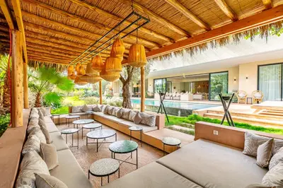 an outdoor living room with couches and tables and a pool at Villa Aila Elegant 6 Bedrooms Spa, Cinema Pool in Marrakech