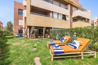 two lounge chairs in the grass in front of a building at Charme Marrakchi - Piscine, Jardin & Espace Sport in Marrakech