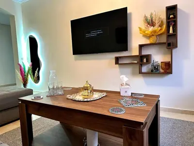a living room with a table with a television on the wall at Appartement charmant au cœur de Marrakech in Marrakech