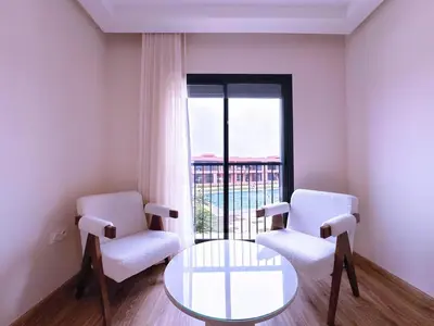 a room with two chairs and a glass table and a window at New! apptÉlégance ,Lumière et Confort avec piscine in Marrakech