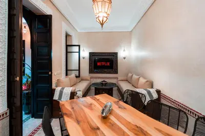 a living room with a table and a tv at Riad Sahar Privé - Piscine Chauffée Sup - PDJ Inclus in Marrakech