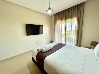 a bedroom with a large bed and a television at Prestigia aghat in Marrakech