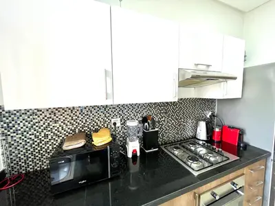 a kitchen with a black counter top with a microwave at Prestigia aghat in Marrakech