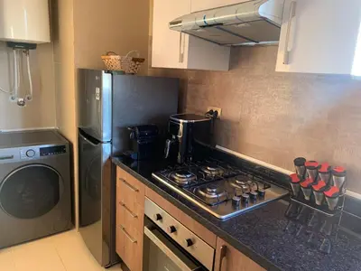 a kitchen with a stove top oven next to a washing machine at Prestigious new 3-bedroom apartment with pool view in Marrakech