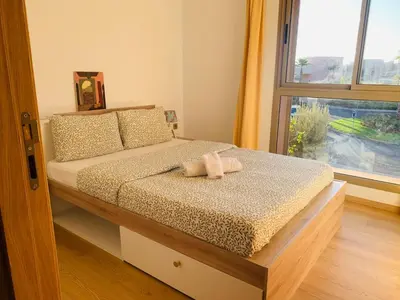 a bedroom with a bed with two pillows and a window at Prestigious new 3-bedroom apartment with pool view in Marrakech