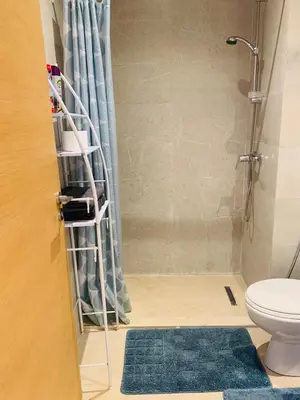 a bathroom with a shower with a toilet and a blue rug at Prestigious new 3-bedroom apartment with pool view in Marrakech