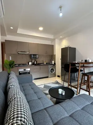 a living room with a gray couch and a kitchen at Noria Golf Poolside Garden Flat in Marrakech