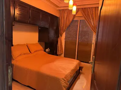 a bedroom with a bed with orange sheets and a window at Appartement al acadimya in Marrakech