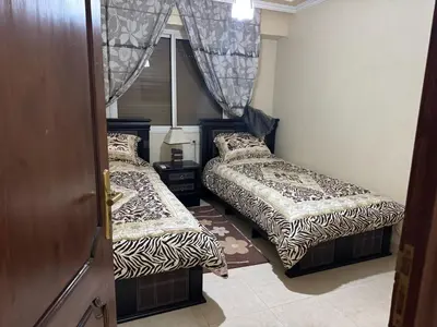 two beds in a small room with a door at Appartement al acadimya in Marrakech