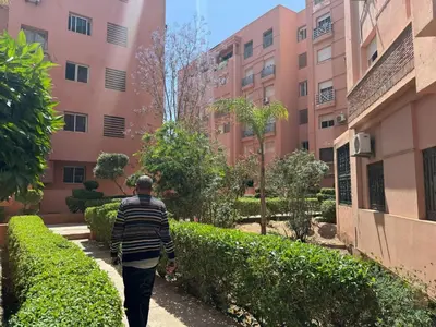 a man walking down a sidewalk in front of a building at Appartement al acadimya in Marrakech