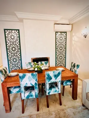 a dining room with a wooden table and chairs at Apprt luxueux l'Hivernage au centre ville proche de la gare ,M avenu CR07 in Marrakech