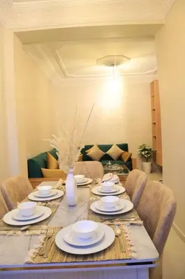 a dining room table with plates and a vase on it at Apartment 5 minutes from Marrakech Airport in Marrakech