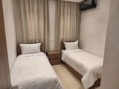 two beds in a hotel room with white sheets at Apartment 5 minutes from Marrakech Airport in Marrakech