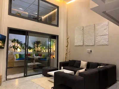 a living room with a couch and a table at Magnifique loft haut de gamme avec grande terrasse zen et fontaine murale situé en plein centre-ville de Marrakech dans le cœur du quartier Gueliz à proximité des rues commerçantes et animées du Carré Eden et du Plaza Dépôt de garantie obligatoire in Marrakech