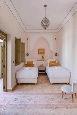 a bedroom with two beds and a table and a chandelier at Riad Bayda in Marrakech