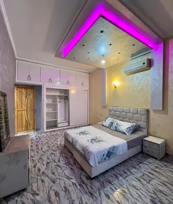 a bedroom with a large bed with a pink lighting at Appartement spacieux de luxe familial in Marrakech