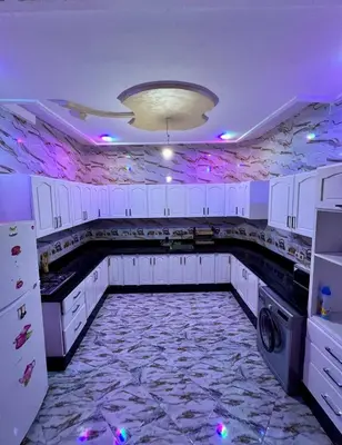 a kitchen with white cabinets and a marble floor at Appartement spacieux de luxe familial in Marrakech