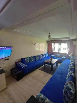 a living room with a blue couch and a tv at Résidence les amis 2 chambres appartement familial in Marrakech