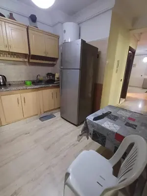 a kitchen with a refrigerator and a table and a chair at Résidence les amis 2 chambres appartement familial in Marrakech