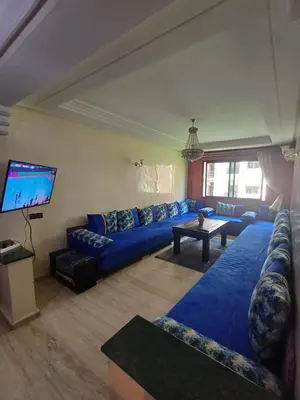 a living room with blue couches and a flat screen tv at Résidence les amis 2 chambres appartement familial in Marrakech