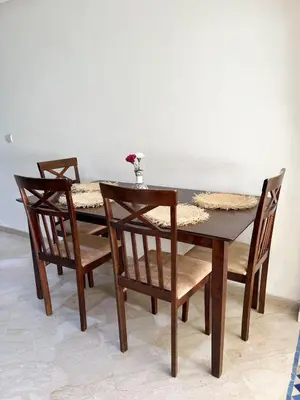 a wooden table with four chairs and a vase of flowers on it at Stylish Stay downtown in Marrakech