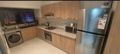 a kitchen with a stainless steel refrigerator and wooden cabinets at Kech Amal Apartment in Marrakech