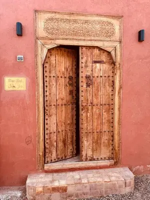 a pair of wooden doors on the side of a building at Dar Tal, Marrakech in Douar Oulad Ali