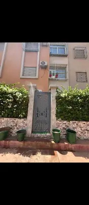 a door in front of a building with two green pots at Appartement calme chez Nawal in Marrakech