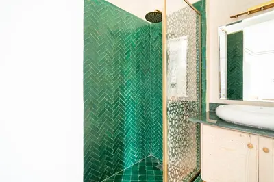 a bathroom with a green tiled shower with a sink at Riad Dar Rafaël in Marrakech