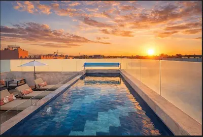 a pool on the roof of a building with the sunset at Triplex De Luxe Ocra piscine privée in Marrakech