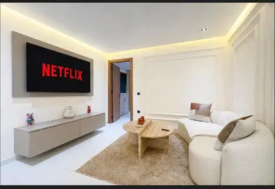 a living room with a white couch and a tv at Triplex De Luxe Ocra piscine privée in Marrakech
