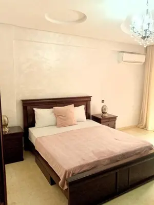 a bedroom with a bed and two tables and a chandelier at Appartement en plein centre in Marrakech