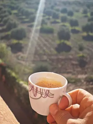 a person holding a cup of coffee in front of a window at Ennaim in Marrakech