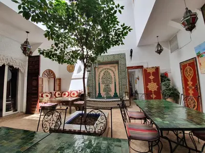 a room with a table and chairs and a tree at Riad Alma Mouassine in Marrakech