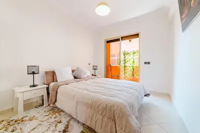 a white bedroom with a large bed and a window at Appartement Malika Gueliz in Marrakech