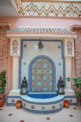 a large fountain in a room with a tile wall at Charming Private Riad in Marrakech