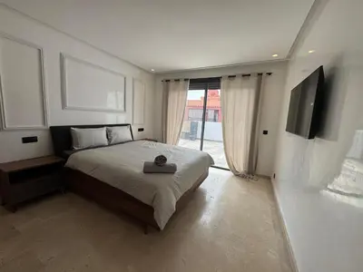 a bedroom with a large bed and a television at Splendide dernier étage plein coeur de Guéliz et Carré Eden in Marrakech
