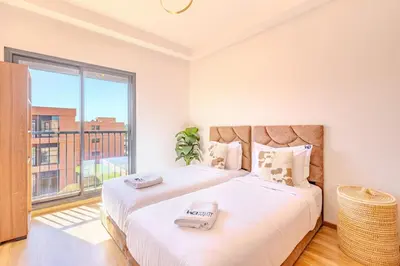 two beds in a bedroom with a large window at New! Appt moderne avec terrasse et vue piscine in Marrakech