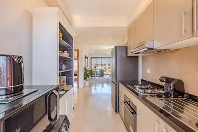 a kitchen with white cabinets and a stove top oven at New! Appt moderne avec terrasse et vue piscine in Marrakech