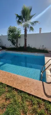 a blue swimming pool with a palm tree in the background at VILLa PALMS KECH in Marrakech