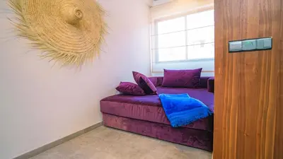 a purple couch in a room with a window at Appartement chaleureux agréable pour des vacances en famille in Marrakech