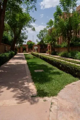 a walkway in a park with trees and grass at Un magnifique appartement avec jardin à Marrakech in Marrakech
