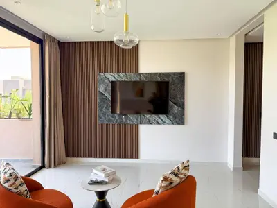 a living room with two orange chairs and a television at VILLA DE LUXE à Marrakech, GOLF, Piscine, 10 min du centre in Marrakech