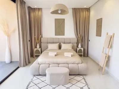 a white bedroom with a large bed and a stool at VILLA DE LUXE à Marrakech, GOLF, Piscine, 10 min du centre in Marrakech