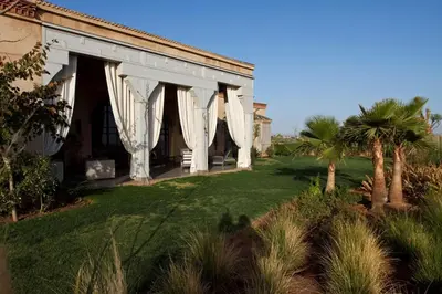 a white building with white curtains on a yard at Villa de luxe avec piscine sur le golf d'amelkis in Marrakech