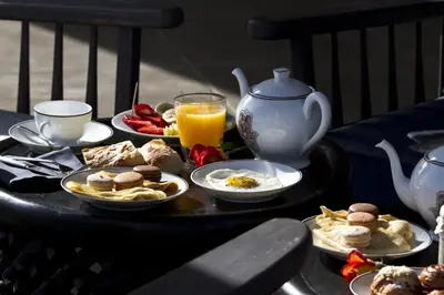 a table with plates of food and a teapot and orange juice at Villa de luxe avec piscine sur le golf d'amelkis in Marrakech