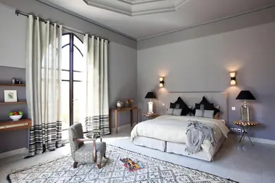 a bedroom with a large bed and a chair at Villa de luxe avec piscine sur le golf d'amelkis in Marrakech